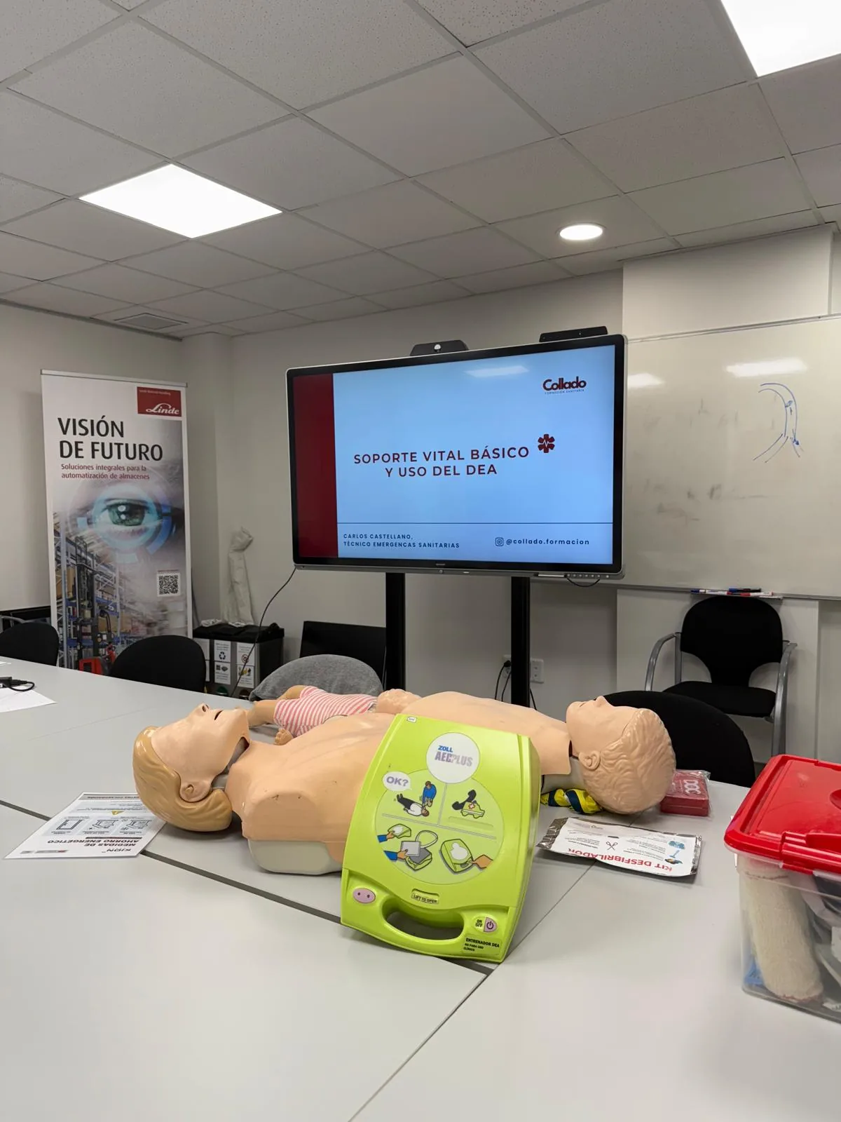 Aula de un curso de Soporte Vital Básico y uso del DEA: maniquíes de adulto y de lactante, desfibrilador de entrenamiento y kit de primeros auxilios sobre la mesa