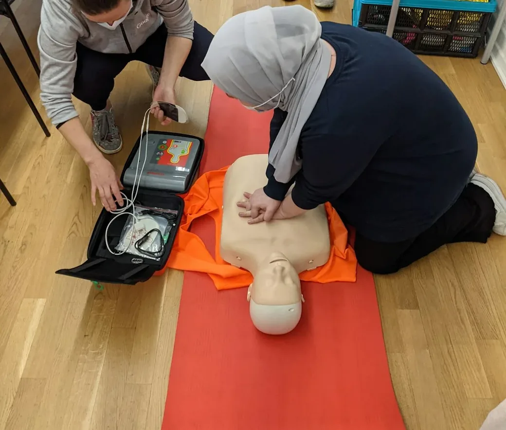 Dos alumnas practican RCP sobre un maniquí junto a un desfibrilador DEA de entrenamiento en un curso de Collado Formación