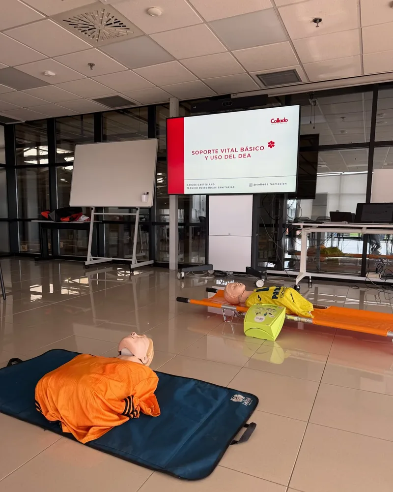 Aula preparada para un curso de Soporte Vital Básico y uso del DEA de Collado Formación, con maniquíes, camilla y desfibrilador de entrenamiento
