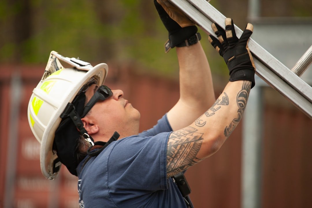 firefighter-in-helmet-adjusts-metal-scaffolding-outdoors-p7pti87ciws